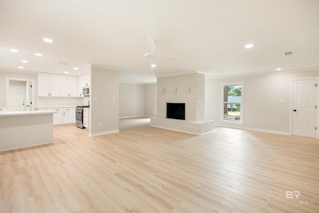 unfurnished living room with ceiling fan, light hardwood / wood-style flooring, ornamental molding, and a brick fireplace