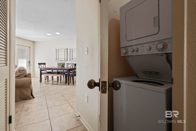 1069 W Beach Blvd Unit 5C, Gulf Shores, AL 36542 - laundry room featuring stacked washer and clothes dryer, light tile patterned floors, and a textured ceiling