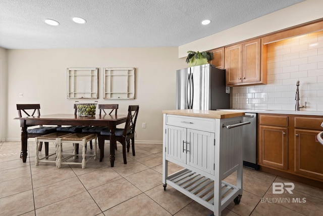 1069 W Beach Blvd Unit 5C, Gulf Shores, AL 36542 - kitchen with stainless steel appliances, light countertops, backsplash, a textured ceiling, and brown cabinets