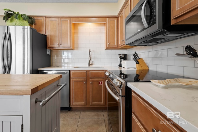 1069 W Beach Blvd Unit 5C, Gulf Shores, AL 36542 - kitchen featuring stainless steel appliances, butcher block countertops, tasteful backsplash, light tile patterned floors, and brown cabinetry