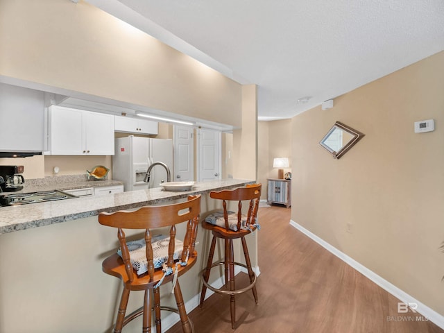 1516 Sandpiper Ln Unit 209, Gulf Shores, AL 36542 - kitchen featuring a breakfast bar, white cabinetry, white fridge with ice dispenser, and light stone countertops