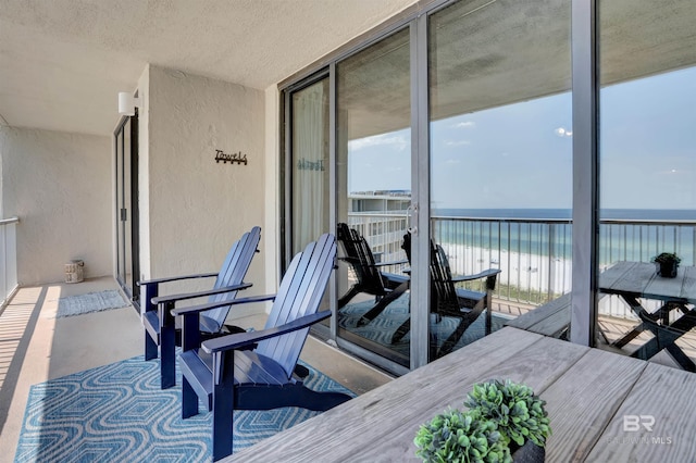 balcony with a water view and a view of the beach