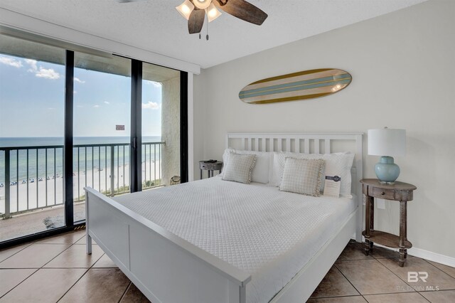 bedroom with access to exterior, a water view, tile patterned floors, and expansive windows
