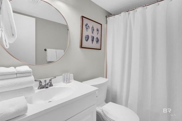 bathroom with vanity, toilet, and a textured ceiling