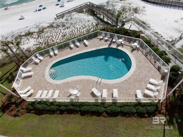 pool with a patio area, a water view, and fence