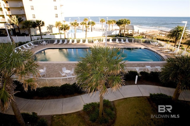 pool featuring a patio, fence, and a water view