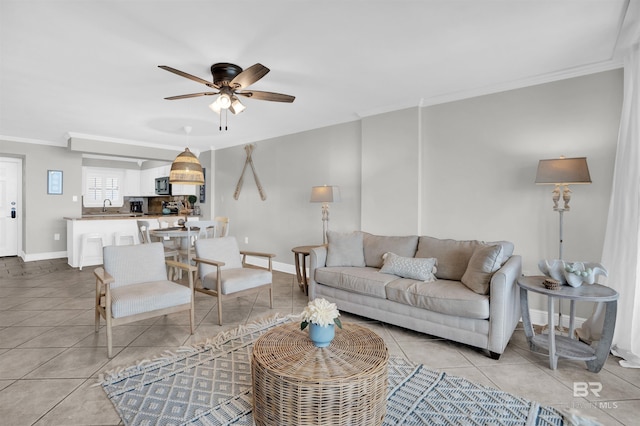 living area featuring light tile patterned floors, baseboards, ornamental molding, and a ceiling fan