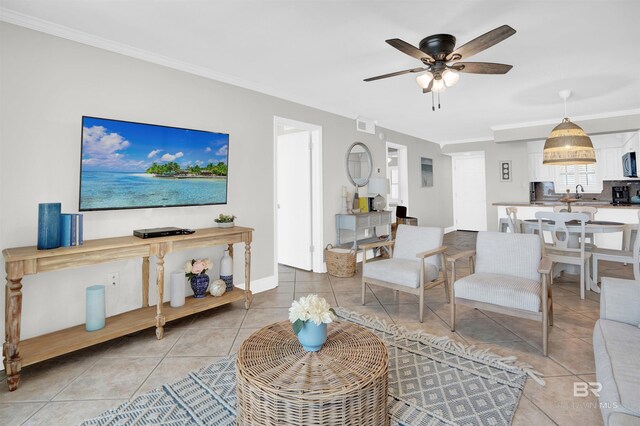 living area with light tile patterned flooring, baseboards, crown molding, and a ceiling fan