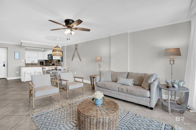 living room featuring crown molding, light tile patterned floors, baseboards, and ceiling fan