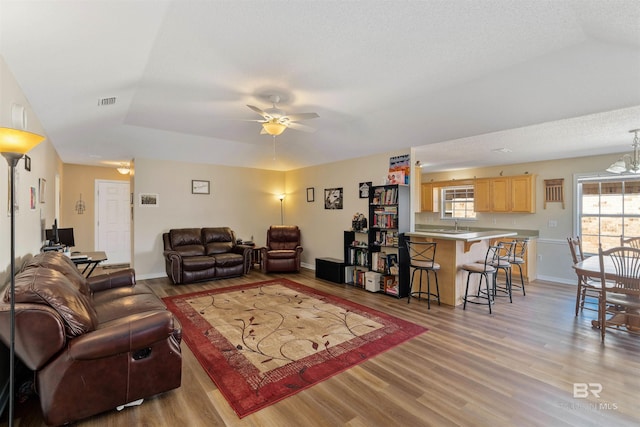 living room with a tray ceiling, a textured ceiling, light wood-type flooring, and ceiling fan