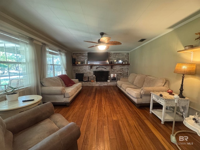 living room featuring dark wood-type flooring, a large fireplace, ornamental molding, and ceiling fan