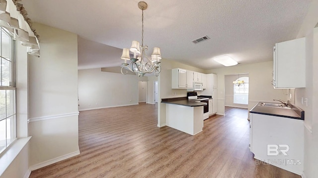 33580 Woodlands Dr, Lillian, AL 36549 - kitchen featuring electric range, white microwave, dark countertops, a chandelier, and light wood-type flooring