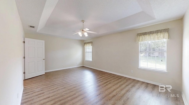 33580 Woodlands Dr, Lillian, AL 36549 - empty room featuring a tray ceiling, wood finished floors, ceiling fan, baseboards, and a textured ceiling