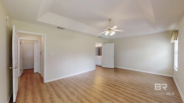33580 Woodlands Dr, Lillian, AL 36549 - empty room with a ceiling fan, light wood-style flooring, baseboards, and a raised ceiling