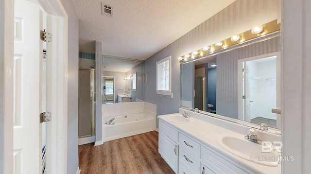 33580 Woodlands Dr, Lillian, AL 36549 - bathroom featuring a shower stall, wood finished floors, a garden tub, double vanity, and a textured ceiling