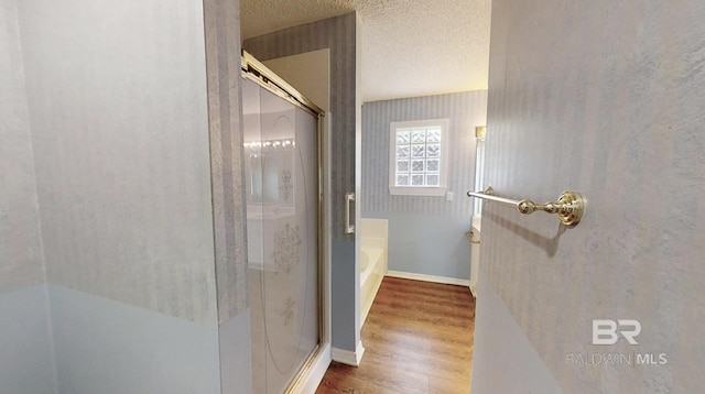 33580 Woodlands Dr, Lillian, AL 36549 - full bath with a stall shower, wood finished floors, a textured ceiling, a bath, and baseboards