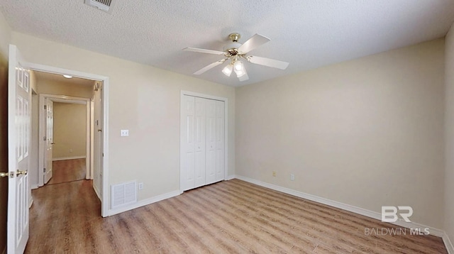 33580 Woodlands Dr, Lillian, AL 36549 - unfurnished bedroom with wood finished floors, a closet, baseboards, a textured ceiling, and a ceiling fan