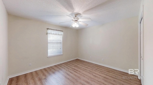 33580 Woodlands Dr, Lillian, AL 36549 - spare room with wood finished floors, ceiling fan, a textured ceiling, and baseboards