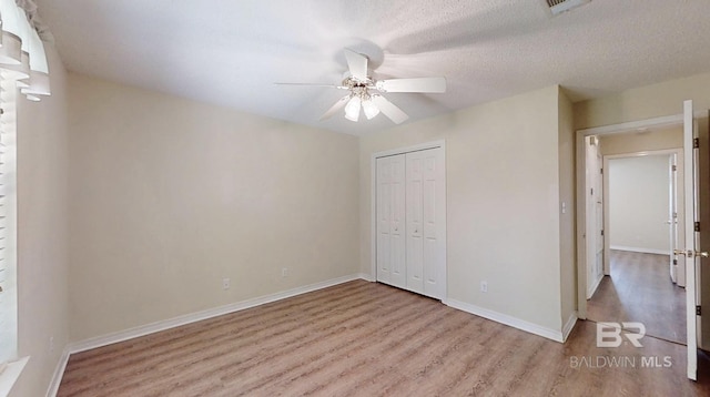 33580 Woodlands Dr, Lillian, AL 36549 - unfurnished bedroom featuring wood finished floors, a closet, baseboards, and a ceiling fan