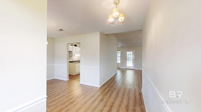 33580 Woodlands Dr, Lillian, AL 36549 - corridor with light wood finished floors, a chandelier, baseboards, and a textured ceiling