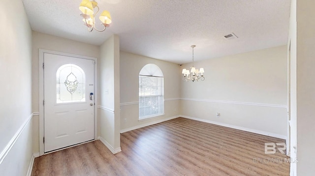 33580 Woodlands Dr, Lillian, AL 36549 - foyer entrance with a chandelier, light wood-style floors, a textured ceiling, and baseboards