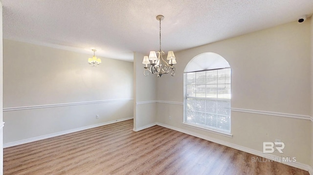 33580 Woodlands Dr, Lillian, AL 36549 - spare room featuring a chandelier, wood finished floors, a textured ceiling, and baseboards