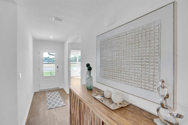 entryway featuring visible vents, light wood-style flooring, a textured ceiling, and baseboards