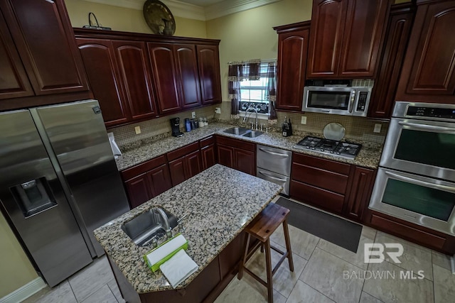 kitchen featuring appliances with stainless steel finishes, sink, a breakfast bar area, and light stone countertops