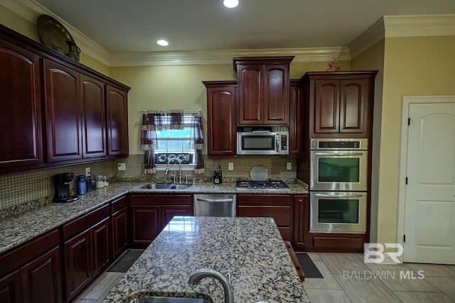 kitchen with appliances with stainless steel finishes, sink, light stone countertops, and backsplash