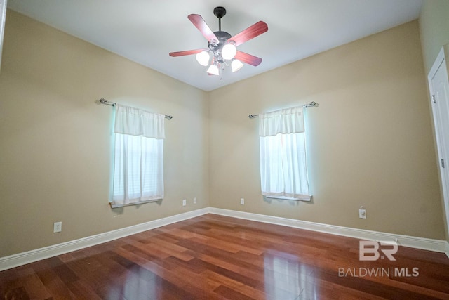 spare room with ceiling fan, plenty of natural light, and wood-type flooring