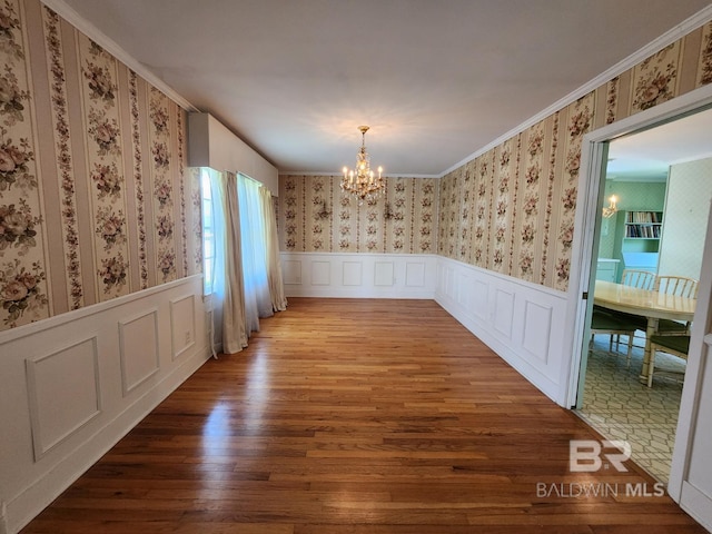 unfurnished dining area featuring ornamental molding, wood-type flooring, and a chandelier