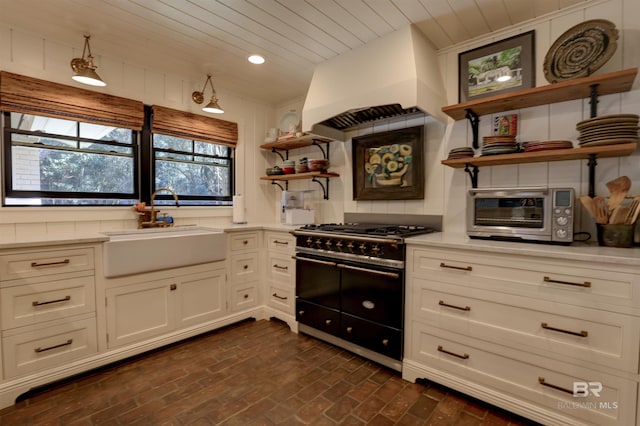 kitchen with brick floor, premium range hood, a sink, double oven range, and open shelves