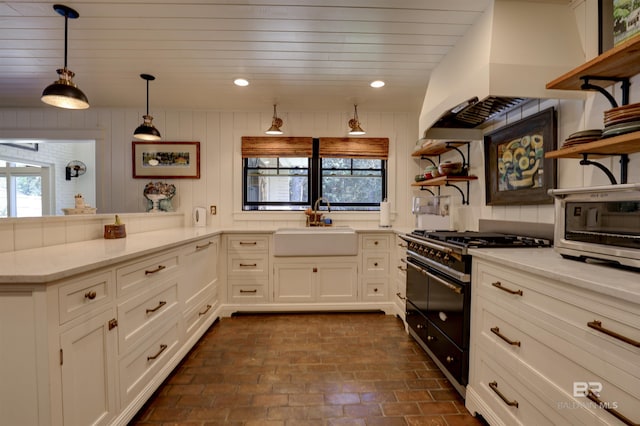 kitchen with range with two ovens, custom range hood, open shelves, and a sink