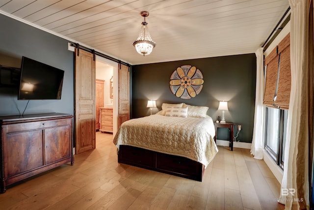 bedroom featuring a barn door, baseboards, wood ceiling, ensuite bathroom, and light wood-style floors