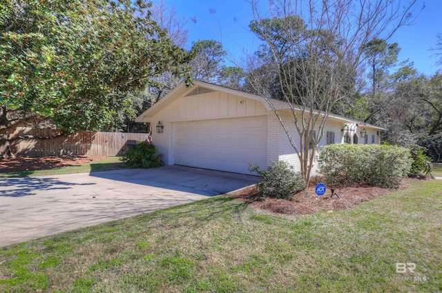 view of property exterior featuring brick siding, concrete driveway, a lawn, an attached garage, and fence