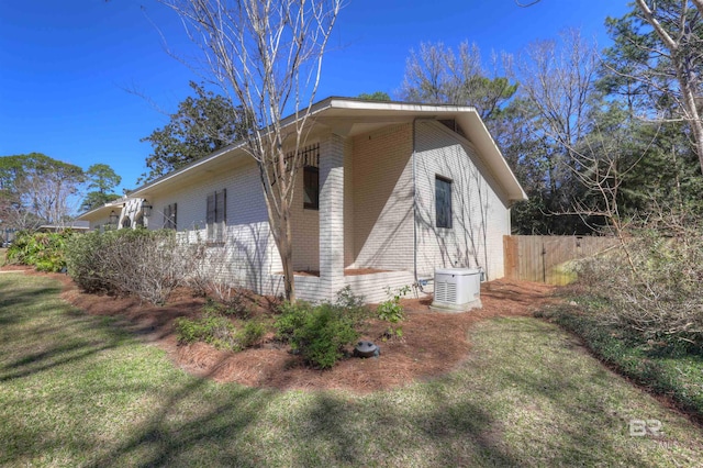 view of home's exterior with a yard, brick siding, and fence