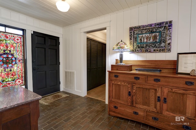 foyer featuring brick floor, visible vents, and ornamental molding