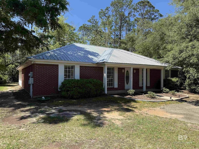 28712 Canal Rd, Orange Beach, AL 36561 - ranch-style home with brick siding, metal roof, a front lawn, and a porch