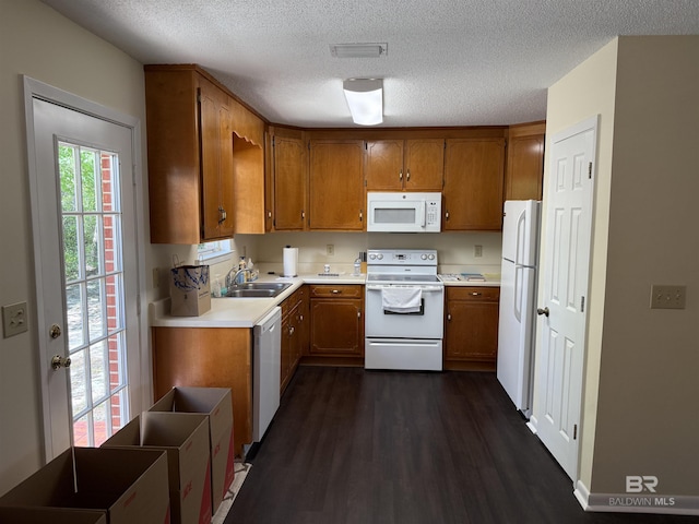 28712 Canal Rd, Orange Beach, AL 36561 - kitchen featuring white appliances, brown cabinets, a sink, dark wood-style floors, and a textured ceiling