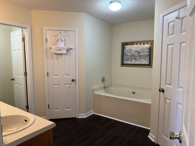 28712 Canal Rd, Orange Beach, AL 36561 - bathroom featuring wood finished floors, a garden tub, a textured ceiling, vanity, and baseboards