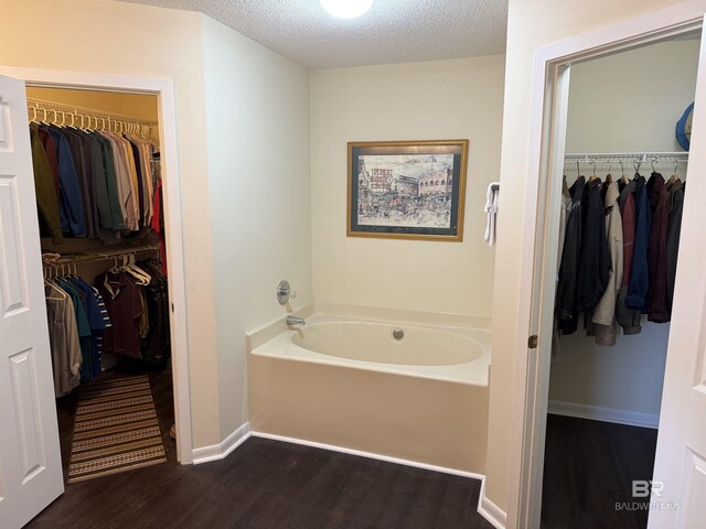 28712 Canal Rd, Orange Beach, AL 36561 - full bathroom featuring wood finished floors, a garden tub, a textured ceiling, baseboards, and a spacious closet