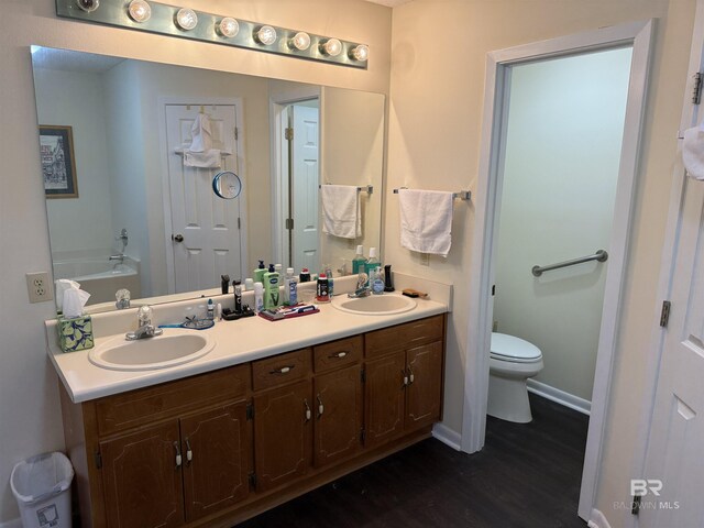 28712 Canal Rd, Orange Beach, AL 36561 - full bathroom featuring wood finished floors, toilet, double vanity, baseboards, and a garden tub