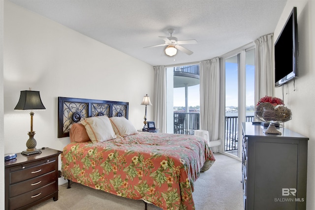 bedroom with expansive windows, a textured ceiling, access to outside, ceiling fan, and carpet
