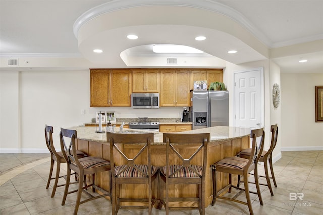 kitchen featuring recessed lighting, ornamental molding, appliances with stainless steel finishes, and light stone countertops