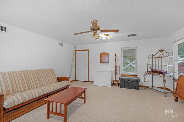 living room with a textured ceiling, plenty of natural light, ceiling fan, and light colored carpet