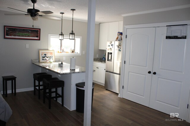 kitchen with white cabinets, a breakfast bar area, dark wood-style flooring, and freestanding refrigerator