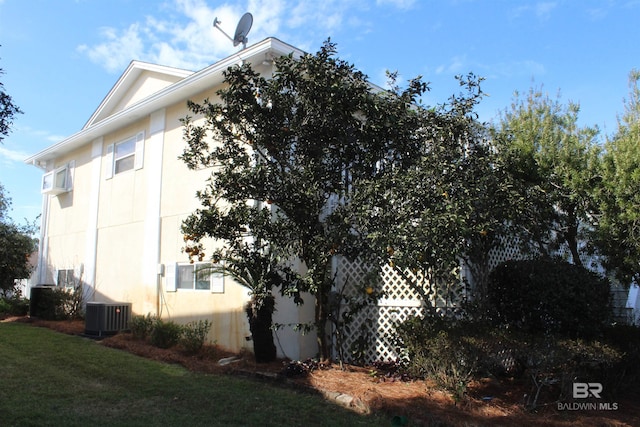 view of side of property with a yard and central AC