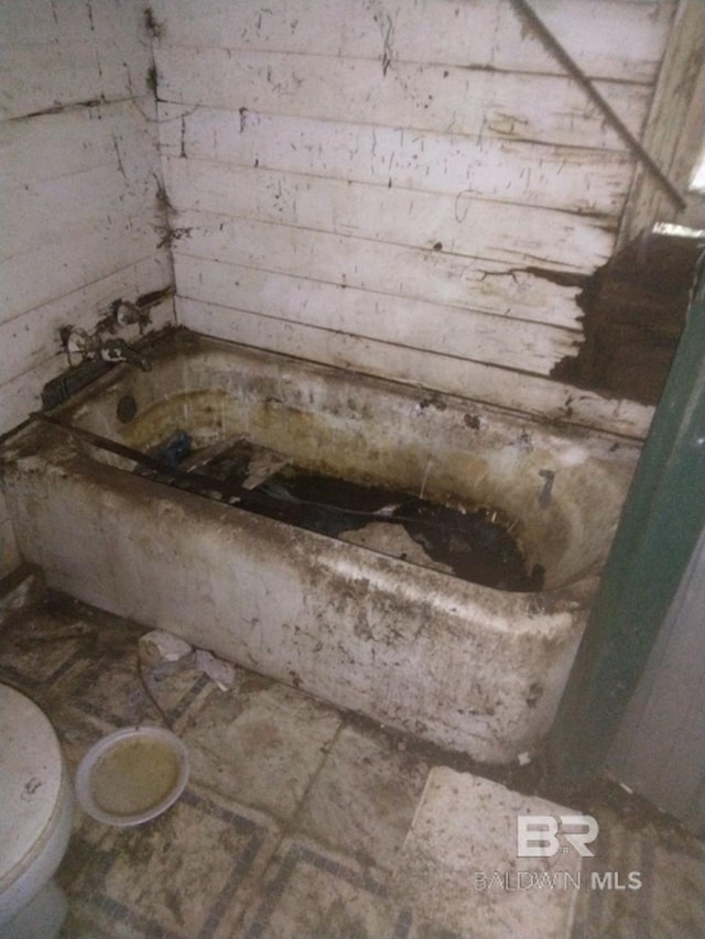 bathroom with a tub to relax in and toilet