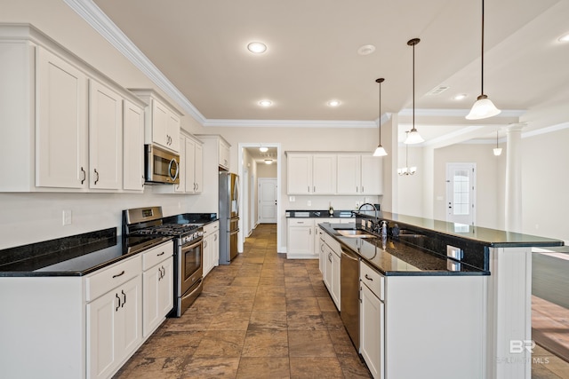 kitchen featuring a kitchen island with sink, dark stone counters, hanging light fixtures, white cabinetry, and stainless steel appliances