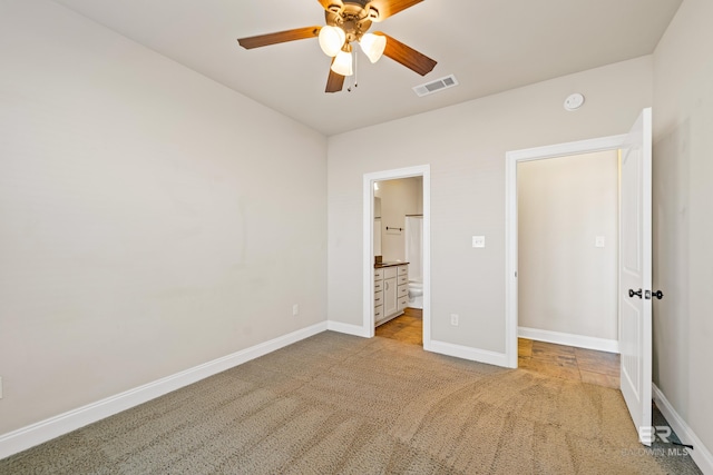 unfurnished bedroom featuring ceiling fan, ensuite bathroom, and light carpet